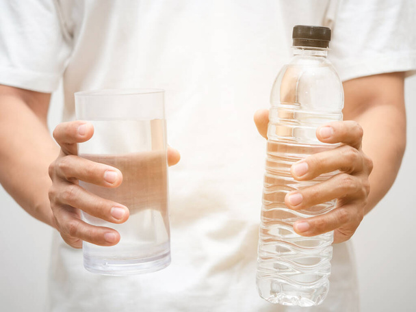 Close up male hands holding glass of water with water bottle - 写真・画像