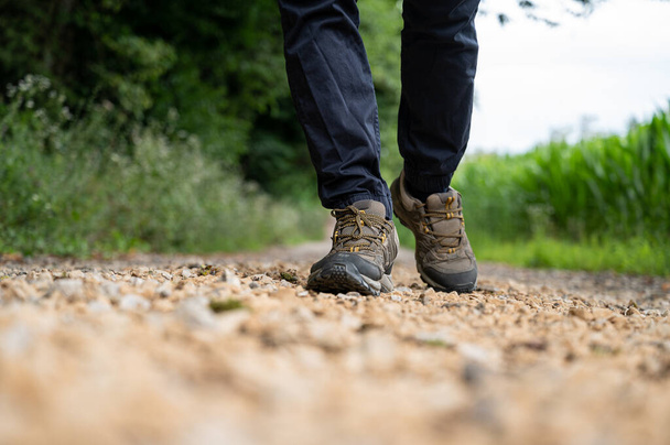 Low angle view of male legs in hiking shoes walking on a trail. - Foto, immagini