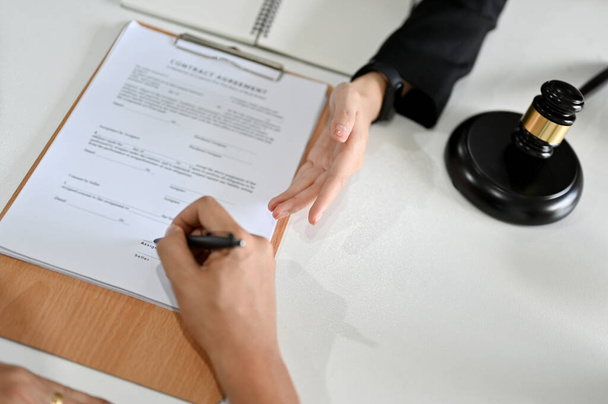 Top view, Businessman client sign his signature on a contract agreement paper in front of his lawyer in the office. close-up image - Photo, Image