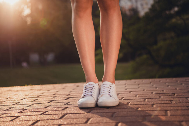Cropped portrait of woman legs standing walking path sun rays light street outside. - Foto, Imagen