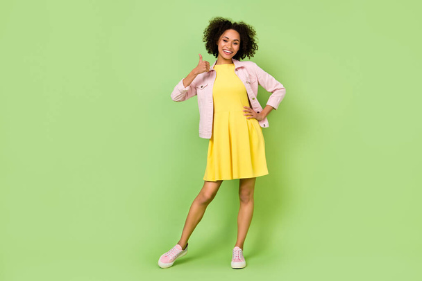Full body photo of cute charming student age girl showing thumb-up promote product isolated on green color background. - Fotó, kép