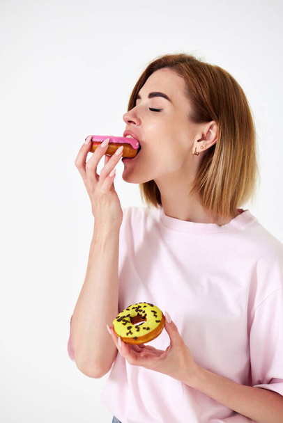 smiling beautiful blonde woman biting donuts isolated on white background. - Фото, изображение