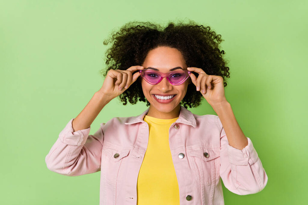 Photo of charming cheerful person hands touch sunglass toothy smile isolated on green color background. - Zdjęcie, obraz