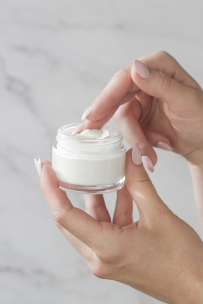 Close up of woman's hand is taking cream from a jar with her finger. Use of cosmetics with natural ingredients for clean and soft skin. Healthcare, skin care and beauty  concept. - Zdjęcie, obraz