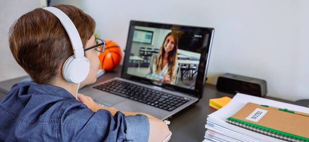 Chlapec se sluchátky doma s laptopem z ložnice. Koncept domácího vzdělávání - Fotografie, Obrázek
