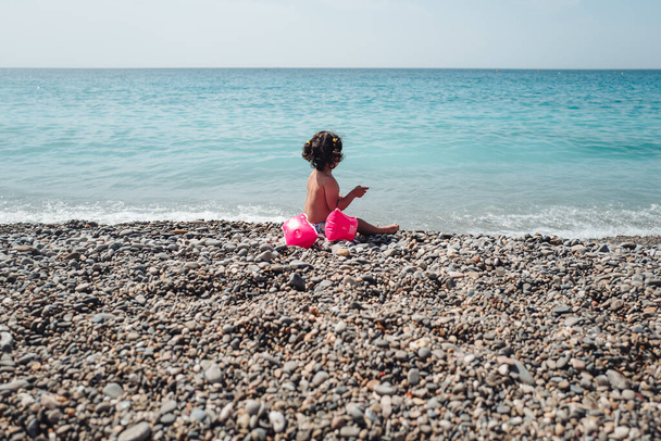 Nice, France-June 2022: a baby girl playing with stones on the beach - Φωτογραφία, εικόνα