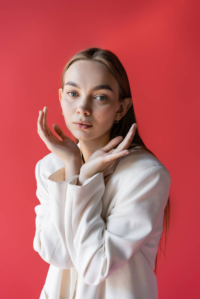 sensual young woman posing with hands near face and looking at camera isolated on pink - Foto, afbeelding