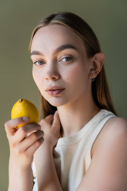 portrait of charming woman with ripe lemon looking at camera isolated on green - Φωτογραφία, εικόνα