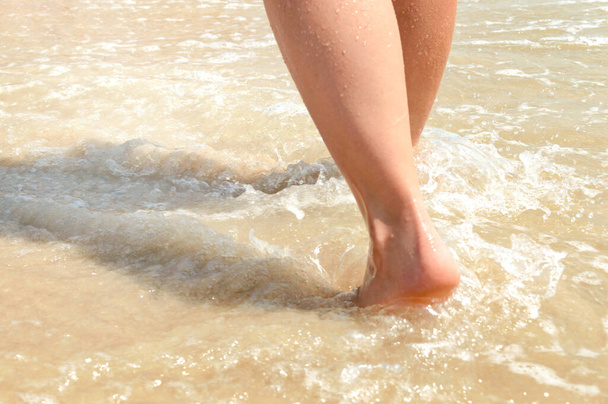 Woman feet walking on beach barefoot, closeup of foot coming out of water. - Foto, imagen