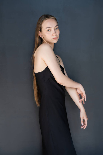 young long haired woman in strap dress looking at camera on black background - Φωτογραφία, εικόνα