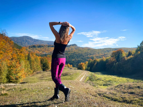 Задний вид на женщину, идущую в горы осенью, смотрящую на красивый пейзаж впереди  - Фото, изображение