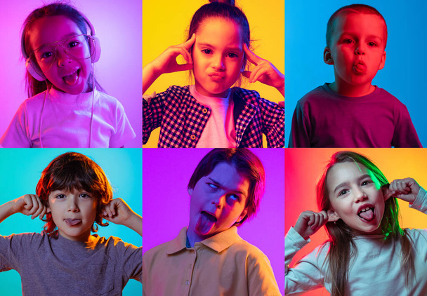 Making faces, grimace. Set of portraits of little cute kids, boys and girls isolated on multicolored background in neon light. Education, wow emotions, facial expression and childhood concept. - Photo, image