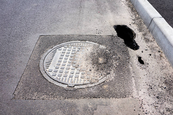 A dip in the asphalt on the road near the sewer manhole. - Photo, Image