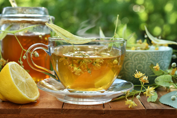 A glass of linden tea with lemon and honey on the table in the garden - Φωτογραφία, εικόνα