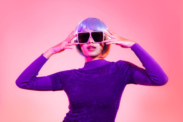 Young asian woman short blue milinium hairstyle wearing pink sunglasses posing on the red pastel and neon color background. - Foto, Imagem