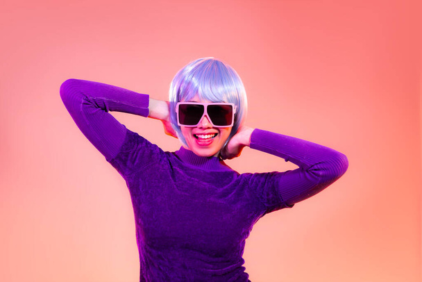 Cyber punk girl concept, happy asian woman in purple sweatshirt wearing sunglasses posing like robot. isolated on red color background. - 写真・画像