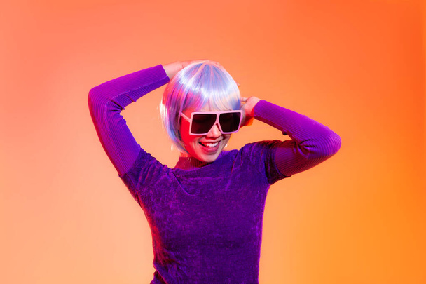 Cyber punk girl concept, asian woman in purple sweatshirt silver and blue short hair style wearing sunglasses posing dancing like robot. - Foto, Imagen