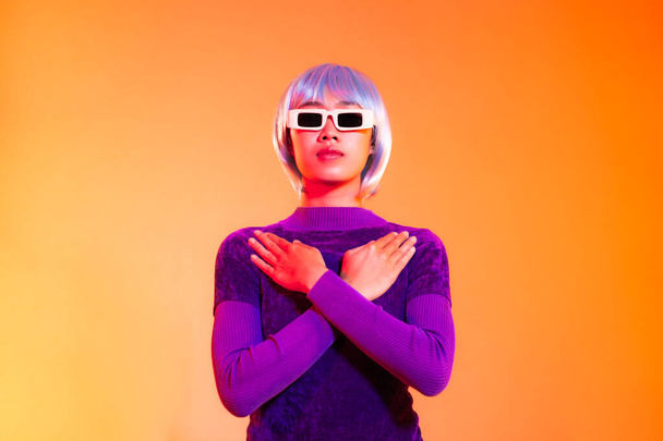 Концепция кибер панк-девушки, азиатка в фиолетовой толстовке и голубой короткой стрижке в солнечных очках, позирующая как робот. - Фото, изображение