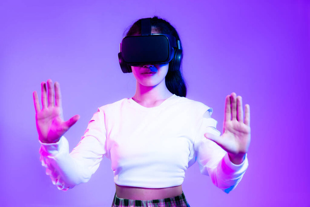 Young asian girl in wearing vr headset watching playing and hands touching on the purple screen background.	 - Фото, изображение