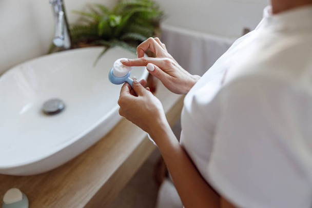 Close up of cleaning facial brush in hands of Caucasian woman in bathroom. High quality photo. - Photo, Image