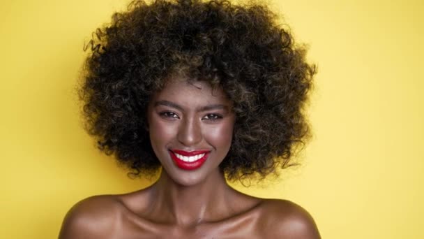 Чорна жінка без сорочки з афро зачіскою і червоними губами, що посилає повітряний поцілунок на камеру ізольовано на жовтому тлі
 - Кадри, відео