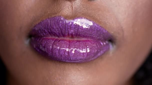 Крупный план на фиолетовых светящихся влажных губах красивой африканской этнической молодой женщины - Кадры, видео
