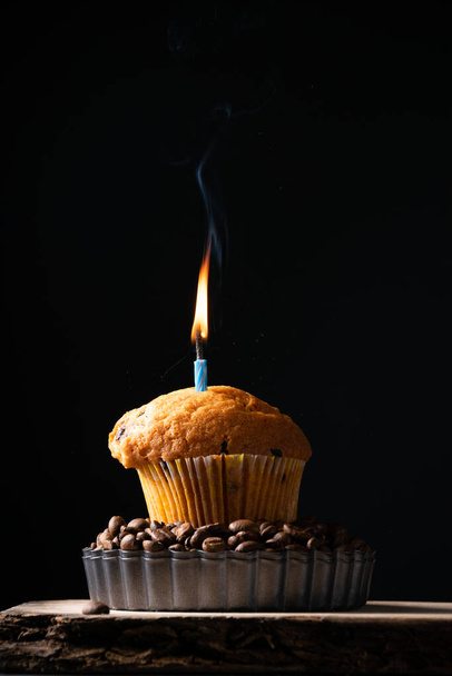 A coffee muffin with lit candle, festive background, baking themes - Fotoğraf, Görsel