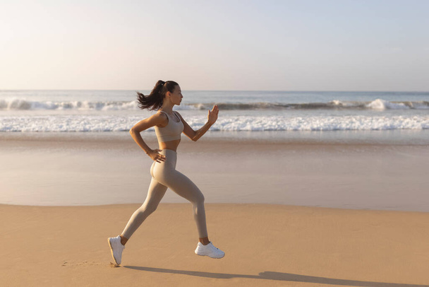 Running woman. Female runner jogging during outdoor workout on beach. Beautiful fit fitness model outdoors. High quality photo - Fotó, kép