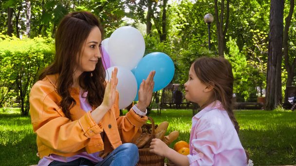 happy mother and daughter playing patty cake game in park - Foto, imagen