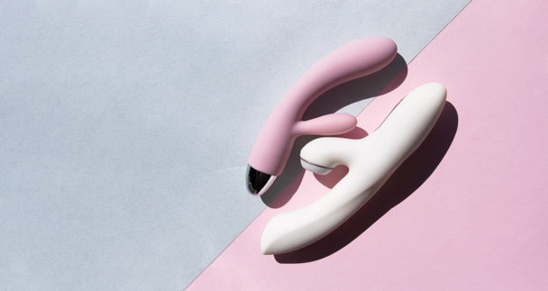 Due giocattoli sessuali per adulti in bianco e rosa si trovano su due sfondi diversi - Foto, immagini