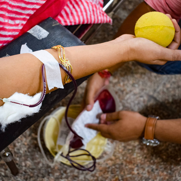 Donneur de sang au camp de don de sang tenu avec une balle pleine d'entrain tenant en main au temple Balaji, Vivek Vihar, Delhi, Inde, Image pour la journée mondiale des donneurs de sang le 14 juin de chaque année, Camp de don de sang - Photo, image