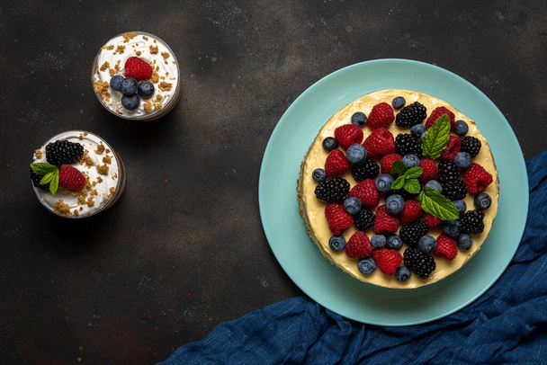 Homemade cake with fresh berries and sweet desserts on dark background.  - Zdjęcie, obraz