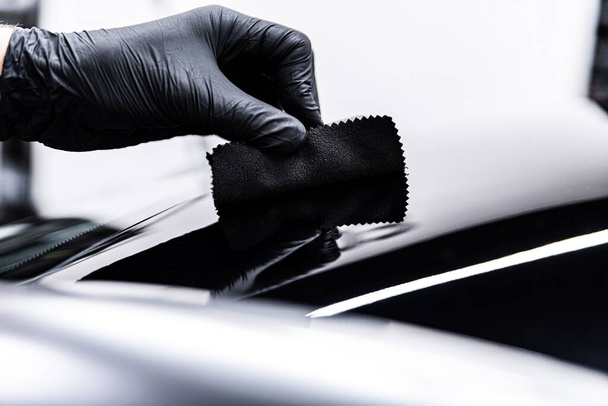 Pracownik myjni samochodowej lub studia detalowego nanosi ceramiczną powłokę na lakier - Zdjęcie, obraz