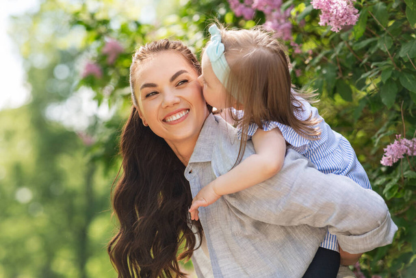 family, motherhood and people concept - happy mother with little daughter having fun at summer park or garden - Фото, изображение
