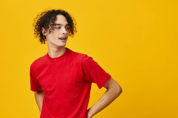 Joyful lovely funny Caucasian young man in red t-shirt posing isolated on over yellow studio background. The best offer with free place for advertising. Emotions for everyday concept - Foto, Imagen