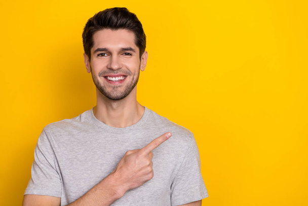 Photo of cute brunet young guy indicate empty space wear trend cloth isolated on yellow color background. - 写真・画像