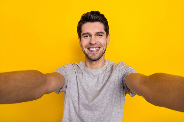 Self-portrait of attractive cheerful guy wearing tsirt good mood isolated over bright yellow color background. - Zdjęcie, obraz