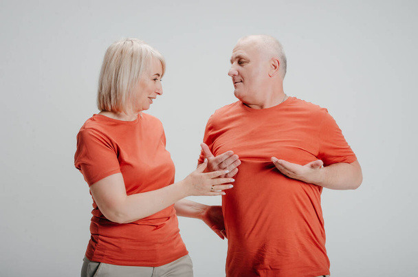 man and woman in orange t-shirts on a white background - 写真・画像