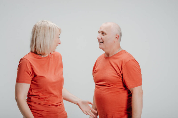 man and woman in orange t-shirts on a white background - Foto, Imagem