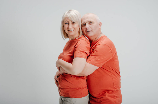 man and woman in orange t-shirts on a white background - Foto, Imagen