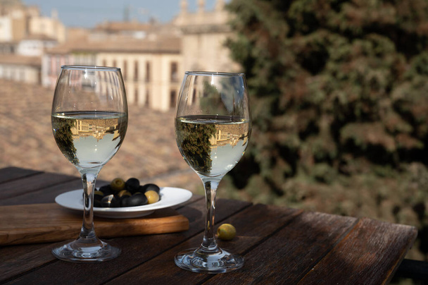 Δύο ποτήρια ισπανικό ξηρό Rueda verdejo λευκό κρασί σερβίρεται με ελιές στην ταράτσα με θέα στο παλιό τμήμα της πόλης της Ανδαλουσίας Γρανάδα, Ισπανία - Φωτογραφία, εικόνα