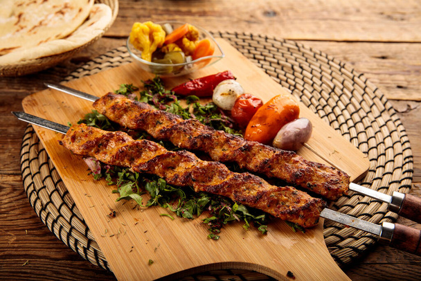 Chicken seekh Kebab served in a wooden cutting board isolated on wooden background side view - Foto, imagen