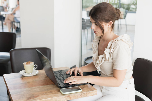 молода жінка має каву під час роботи з ноутбуком
 - Фото, зображення