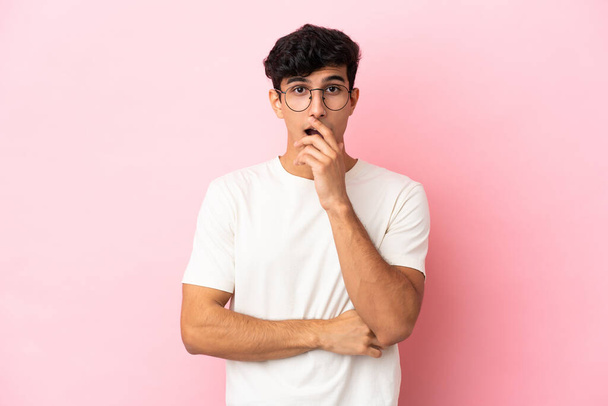 Young Argentinian man isolated on pink background surprised and shocked while looking right - 写真・画像