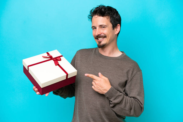 Young man holding a gift and pointing it - Photo, Image