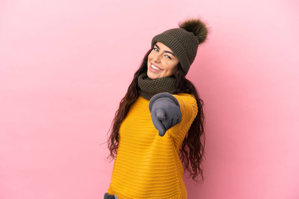 Young caucasian girl with winter hat isolated on purple background pointing front with happy expression - Photo, Image