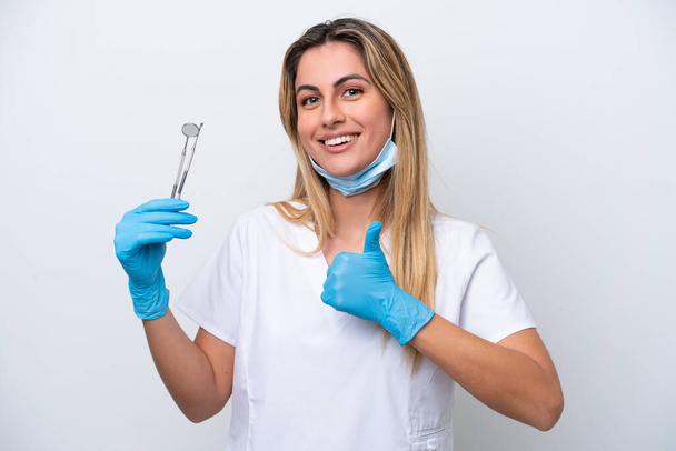 Dentista donna in possesso di strumenti isolati su sfondo bianco dando un pollice in alto gesto - Foto, immagini