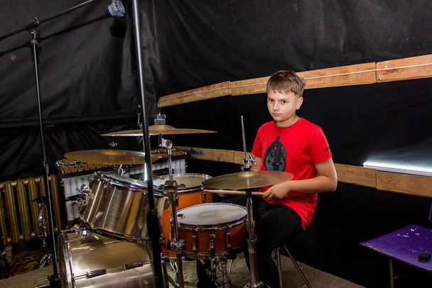 a young drummer plays drums, cymbals with sticks, sitting on a special chair - Foto, imagen