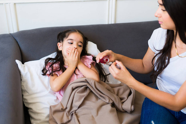 Nemocné malé dítě s chřipkou zakrývající ústa a nechce sirup od své matky  - Fotografie, Obrázek