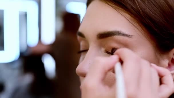 Een mooie brunette vrouw is getint oogleden in een schoonheidssalon. - Video